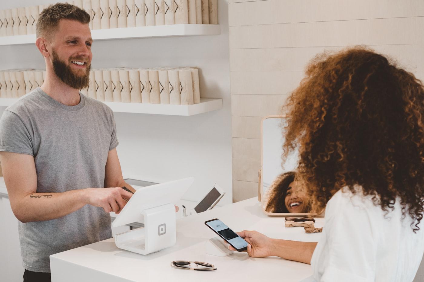 Un commerçant encaisse une cliente en souriant